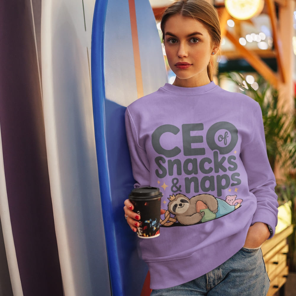 "CEO of Snacks & Naps" printed sweatshirt featuring a sloth in a crown surrounded by pretzels and plushies on vintage-washed cotton fleece