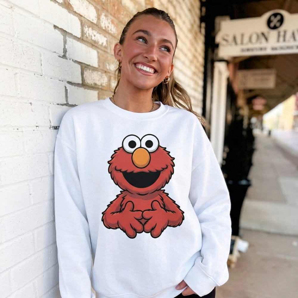 Woman wearing a white sweatshirt with a red character design, standing against a brick wall.
