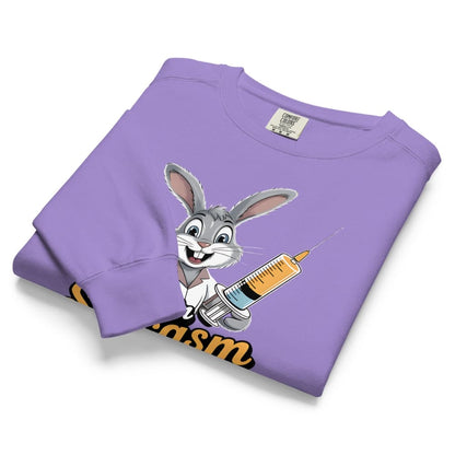 Folded purple sweatshirt with cartoon character and syringe graphic on a white background