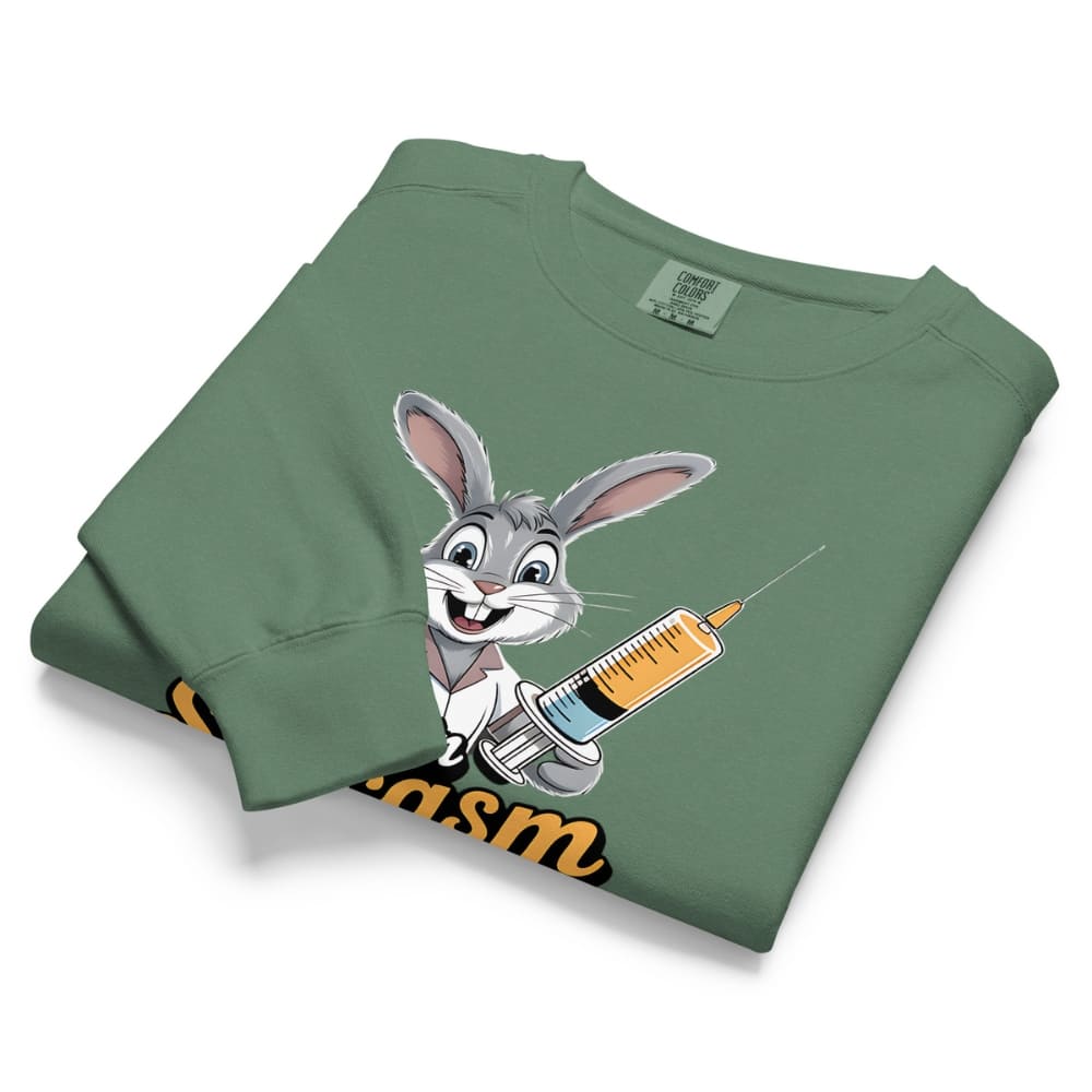 Folded green sweatshirt with cartoon character holding a syringe on a white background