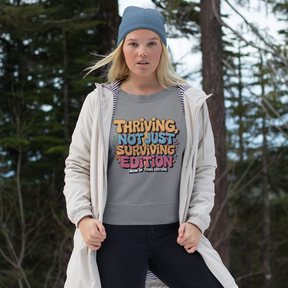 Person wearing a gray sweatshirt with colorful text in a forest setting