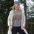 Person wearing a gray sweatshirt with colorful text in a forest setting