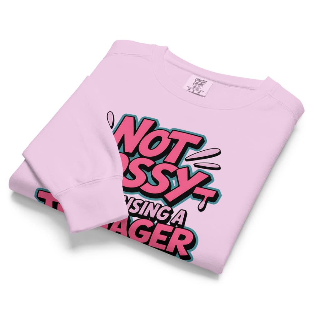 Folded pink sweatshirt with colorful text design on a white background