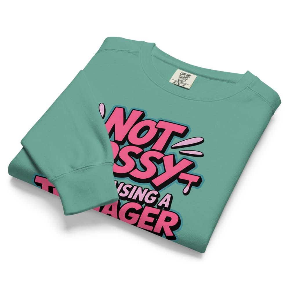 Folded teal sweatshirt with pink and black text on a white background