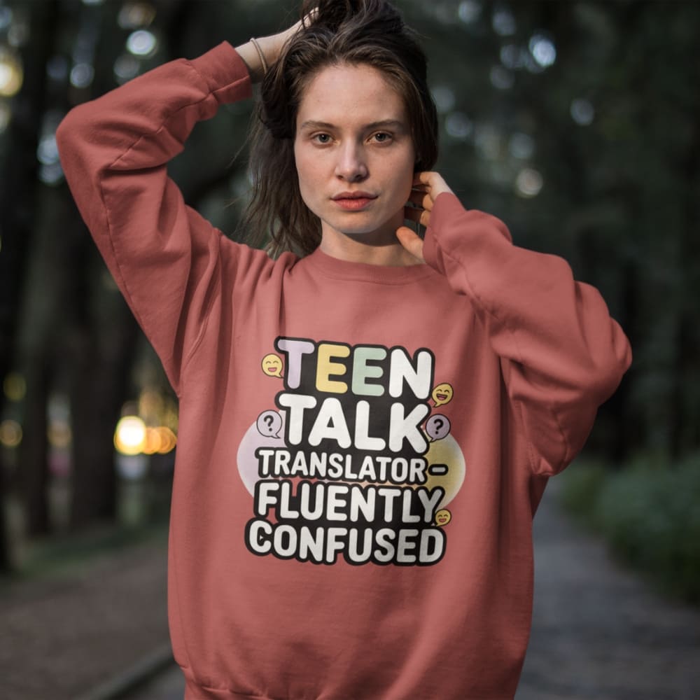 Person wearing a pink sweatshirt with text 'TEEN TALK TRANSLATOR FLUENTLY CONFUSED' outdoors.