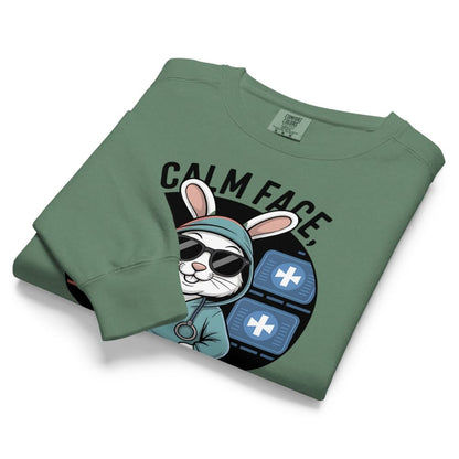 Folded green sweatshirt with a graphic design of a rabbit in a hoodie and sunglasses on a white background.