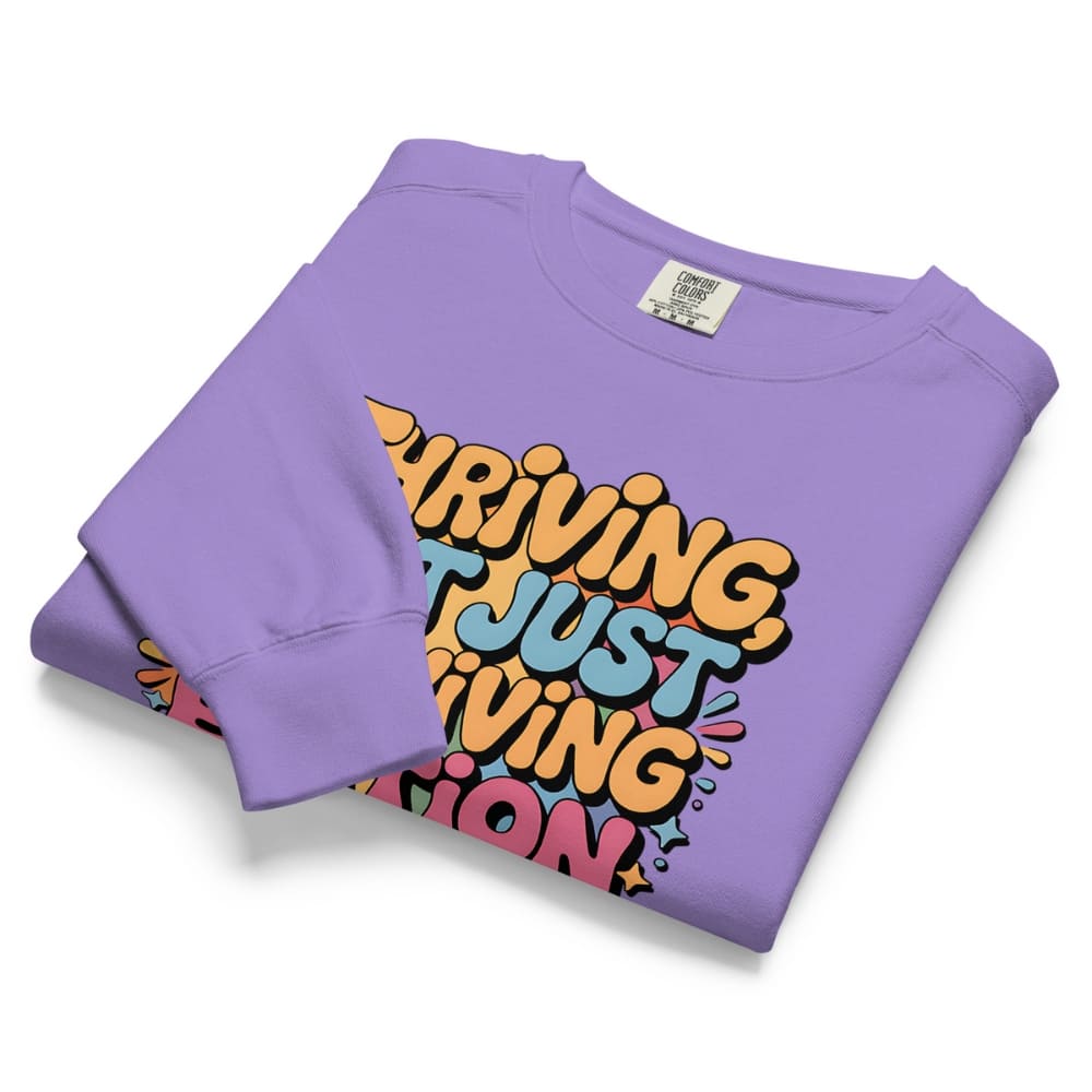 Folded purple sweatshirt with colorful text design on a white background