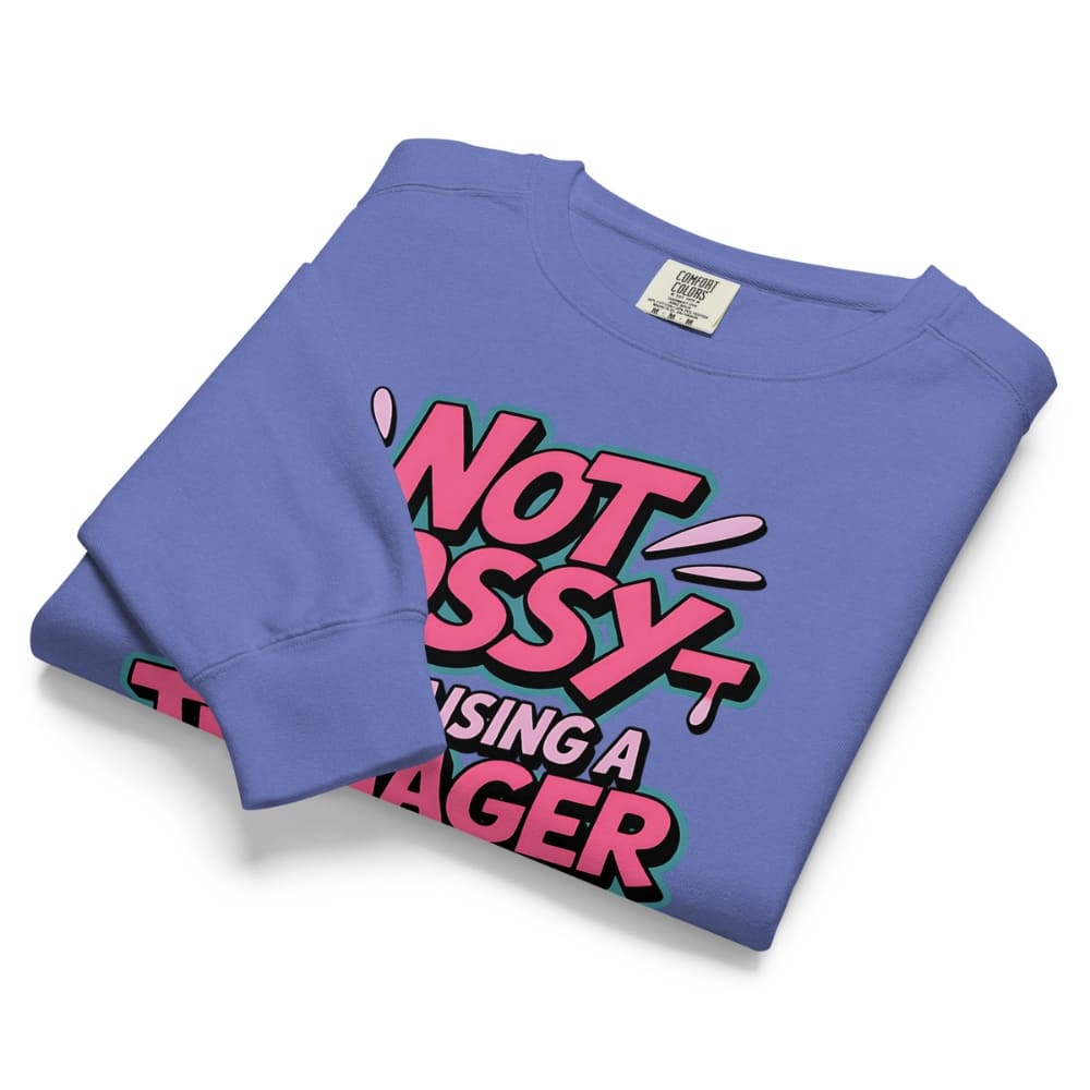 Folded purple sweatshirt with colorful text design on a white background