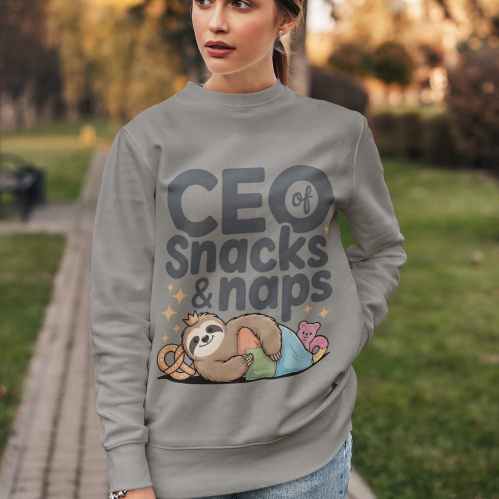 "CEO of Snacks & Naps" printed sweatshirt featuring a sloth in a crown surrounded by pretzels and plushies on vintage-washed cotton fleece