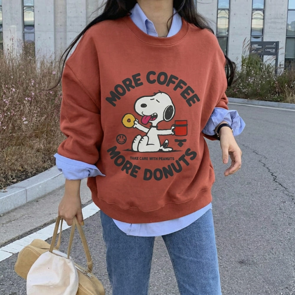 Person wearing a red sweatshirt with a cartoon character and text, standing outdoors.