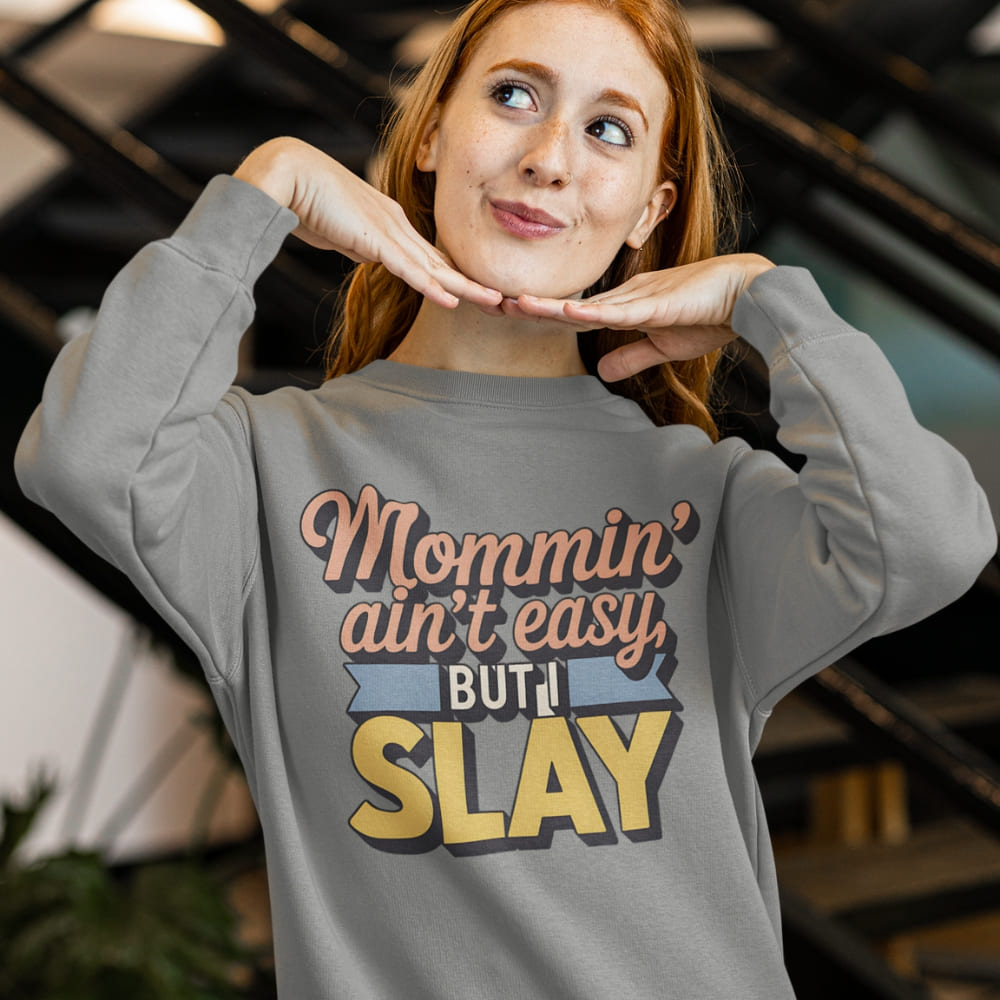 “Mommin' Ain’t Easy But I Slay” retro-style DTG printed design in peach, blue, and yellow on vintage garment-dyed fleece sweatshirt