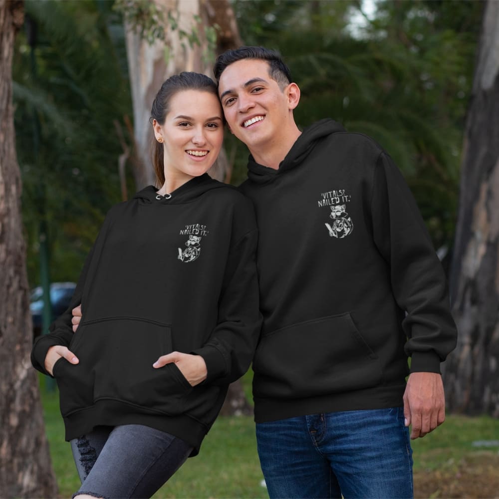 Raccoon nurse graphic wearing scrubs and sunglasses holding a clipboard under the quote “Vitals? Nailed It.” – printed on a black Cotton Heritage hoodie