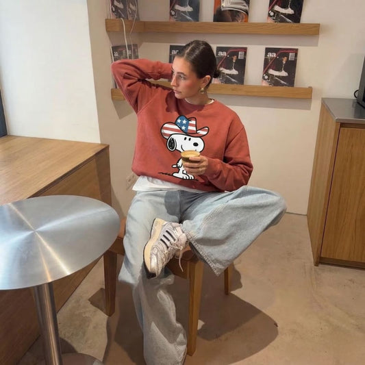 Person wearing a red sweatshirt with a cartoon character, sitting on a chair indoors.