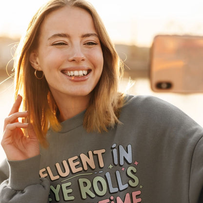 Woman wearing a sweatshirt with colorful text, smiling outdoors.