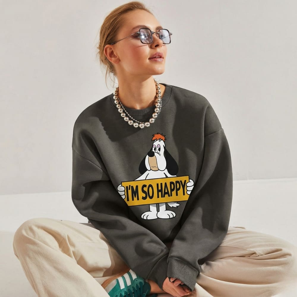 Person wearing a dark gray sweatshirt with a cartoon character and text, sitting on a light-colored couch.