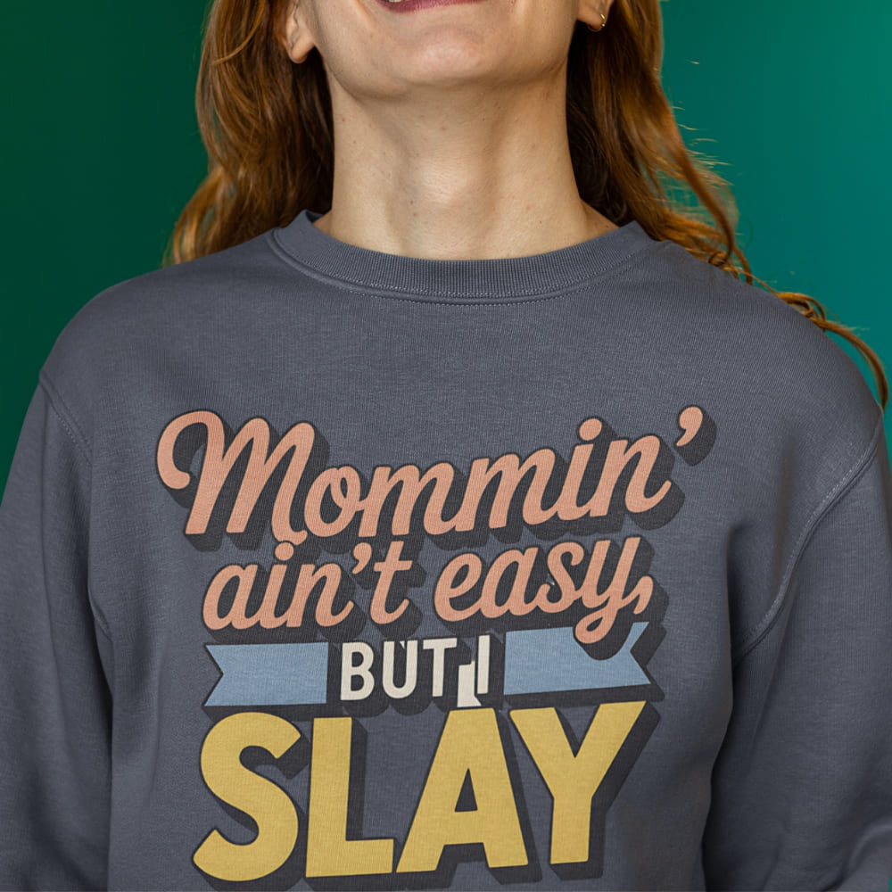 “Mommin' Ain’t Easy But I Slay” retro-style DTG printed design in peach, blue, and yellow on vintage garment-dyed fleece sweatshirt