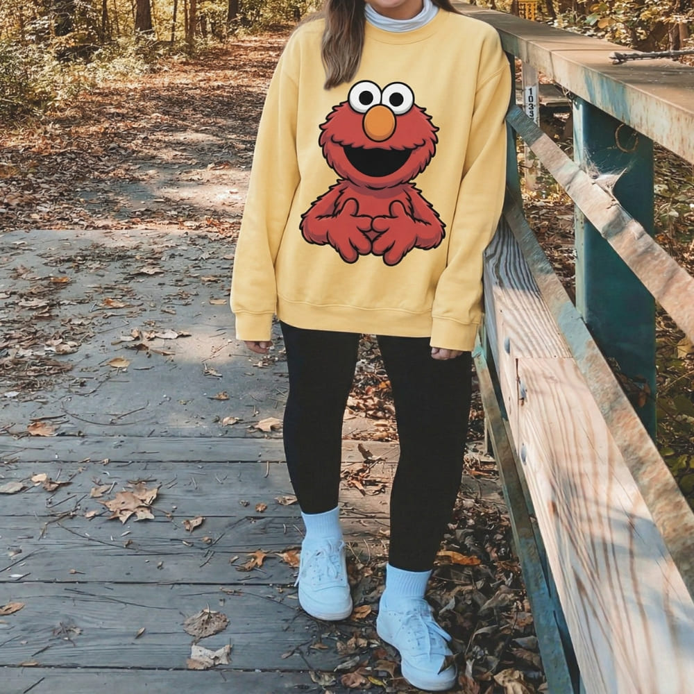 Person wearing a yellow sweatshirt with a cartoon character, standing on a wooden bridge in a forest.
