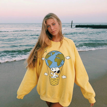 Woman wearing a yellow sweatshirt with a cartoon design on a beach