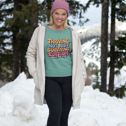 Person wearing a teal sweatshirt with motivational text in a snowy outdoor setting