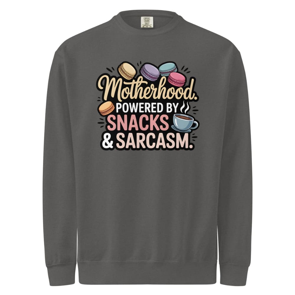 Sweatshirt design with text “Motherhood. Powered by Snacks & Sarcasm.” featuring colorful macarons and a steaming coffee cup on vintage-washed cotton fleece.