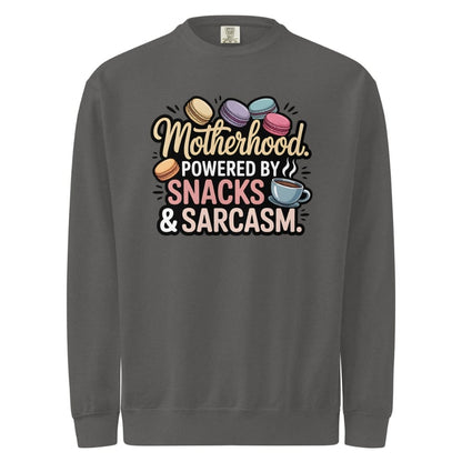 Sweatshirt design with text “Motherhood. Powered by Snacks & Sarcasm.” featuring colorful macarons and a steaming coffee cup on vintage-washed cotton fleece.