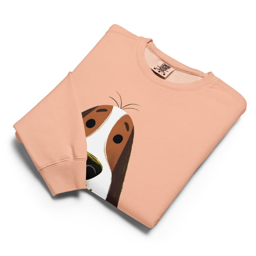 Folded peach-colored sweatshirt with a dog face design on a white background