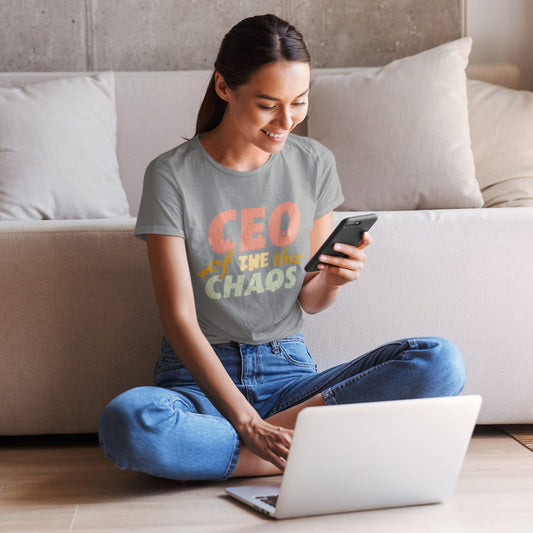 CEO of the Chaos” printed on a heavyweight cotton t-shirt in soft pastel ink, laid flat with a minimal lifestyle background.