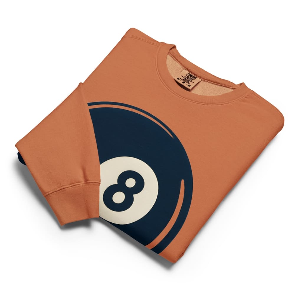 Folded orange sweatshirt with an 8-ball design on a white background