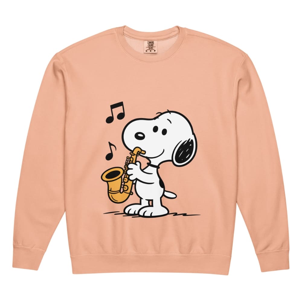 Peach-colored sweatshirt with a cartoon dog playing a saxophone on a white background