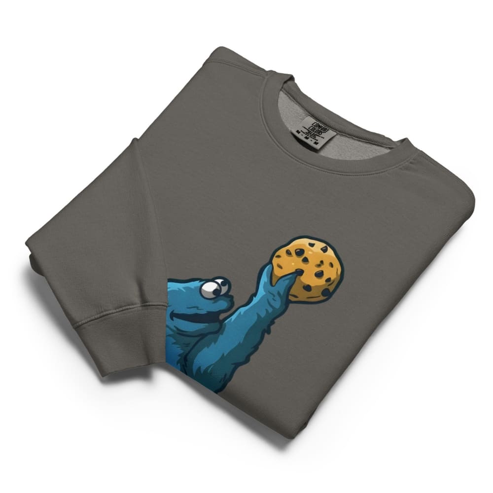 Folded gray sweatshirt with a graphic of a blue creature holding a cookie on a white background