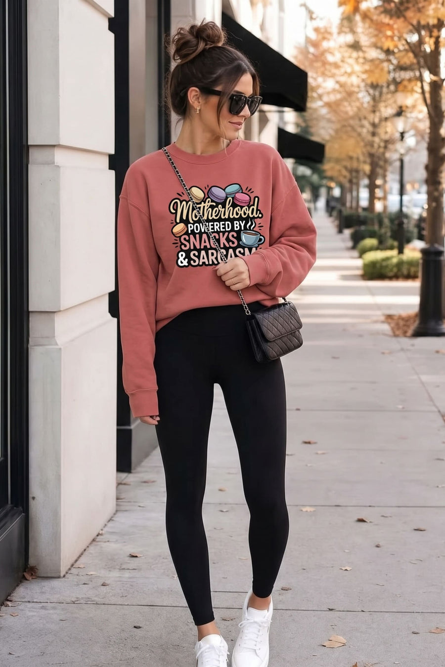 Woman walking a tree-lined city sidewalk in fall wearing the Snacks & Sarcasm™ sweatshirt in Crimson with black leggings and white sneakers
